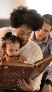 Mother, father, and child enjoying a storybook together in their cozy living room.
