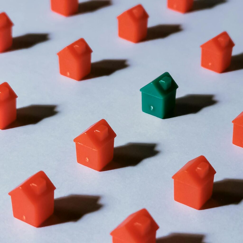Close-up of red and green miniature Monopoly houses on a white background, creating a contrast effect.