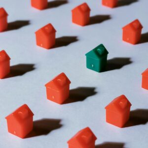 Close-up of red and green miniature Monopoly houses on a white background, creating a contrast effect.